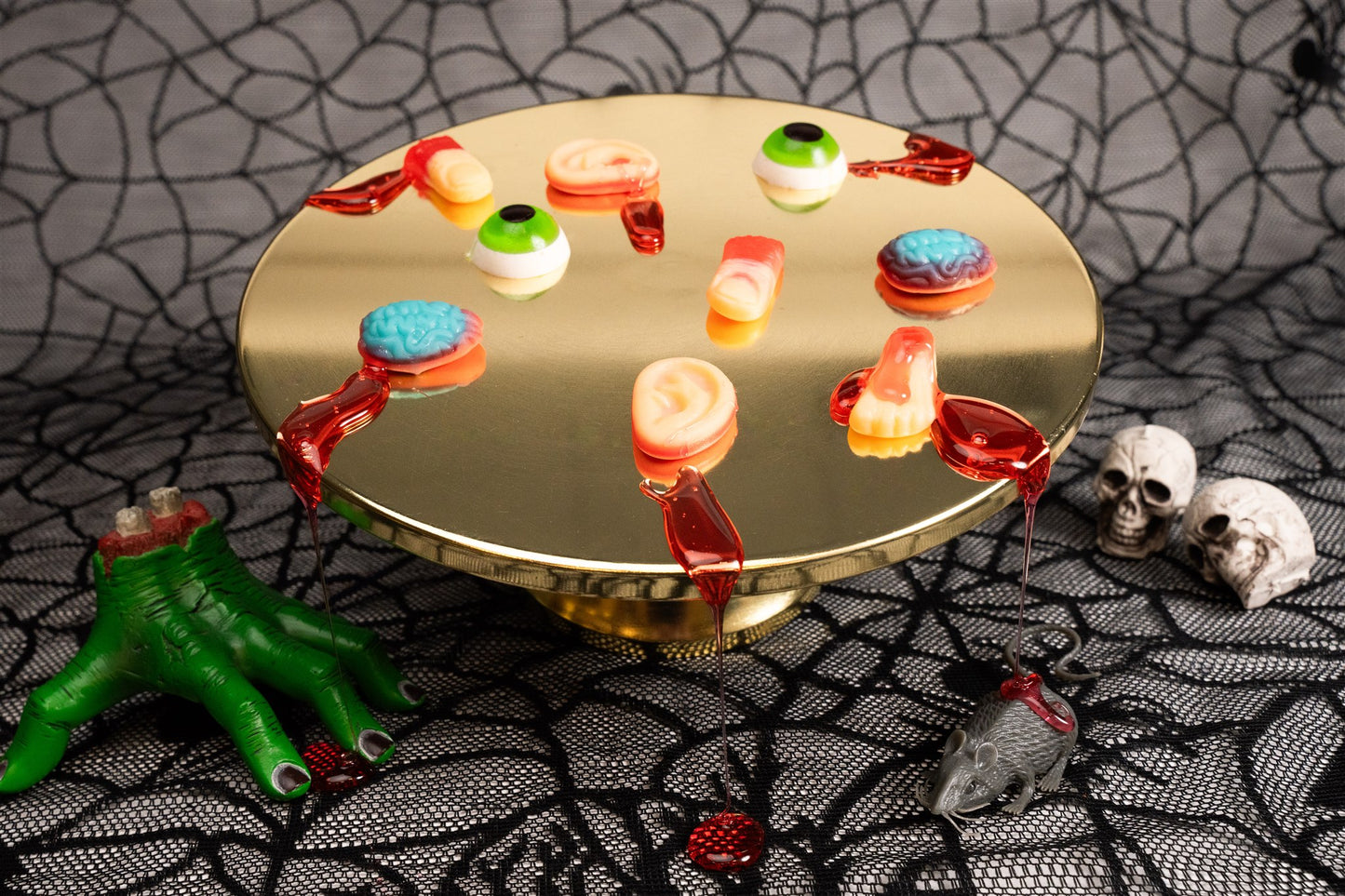 Invidual gummy body parts placed on a gold tray with fake blood decorations. 